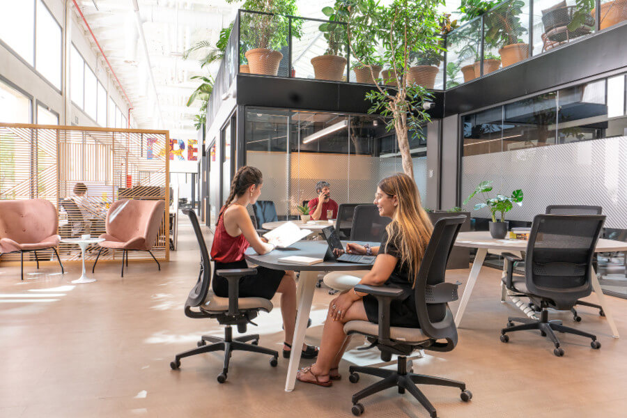 Espacio de coworking abierto con escritorios y sillas blancas.