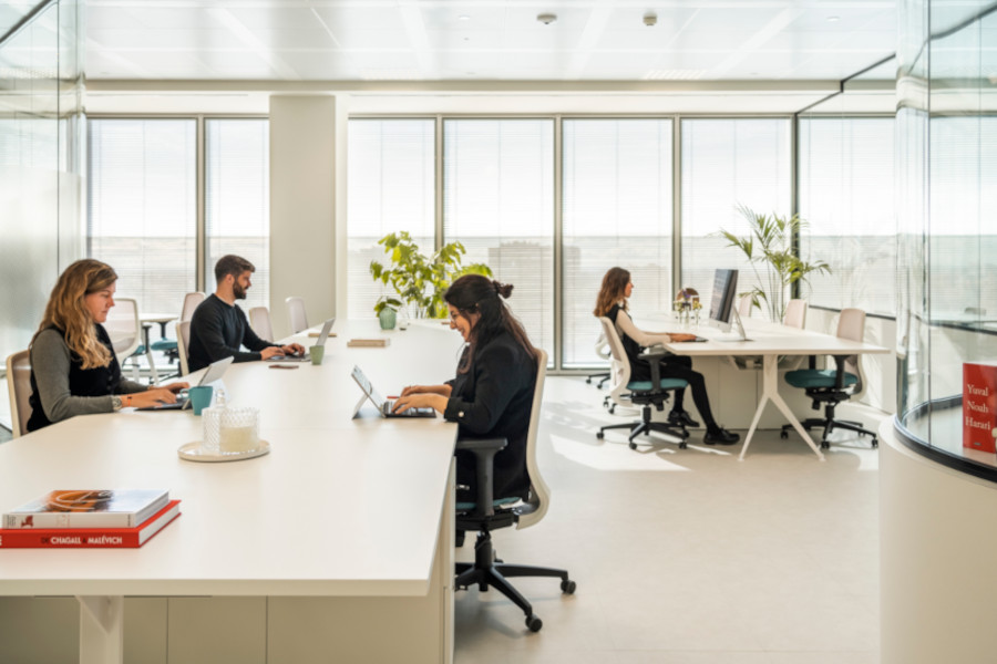 Espacio de coworking abierto con escritorios y sillas blancas.